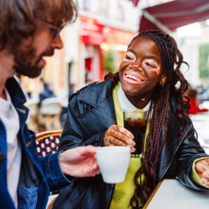 A couple smiling overdrinks at a cafe in Paris.