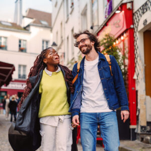 A couple laughing as they walk down a picturesque street in Paris